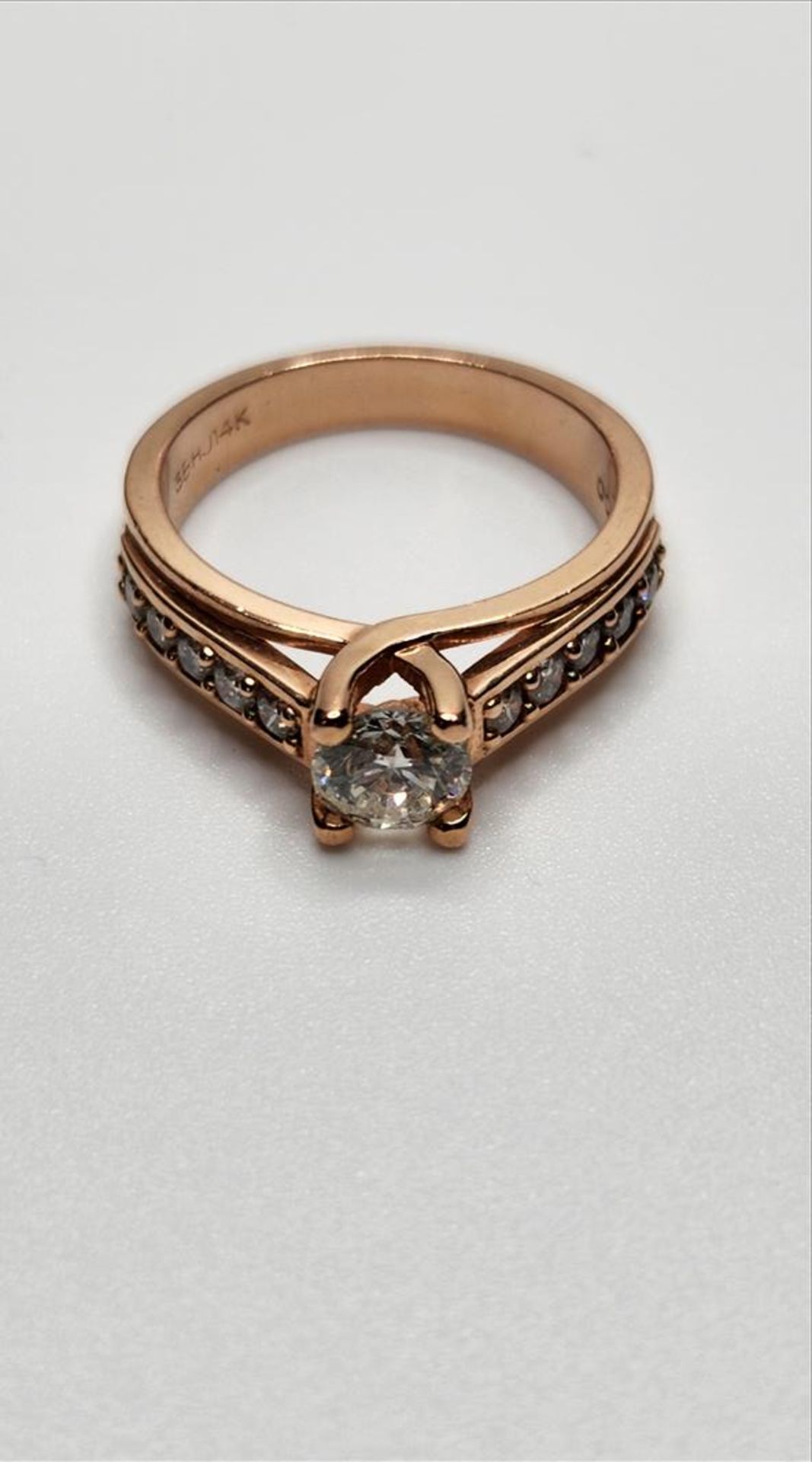 One lady’s stamped and tested 14kt pink gold diamond engagement ring. Contained at the centre is one