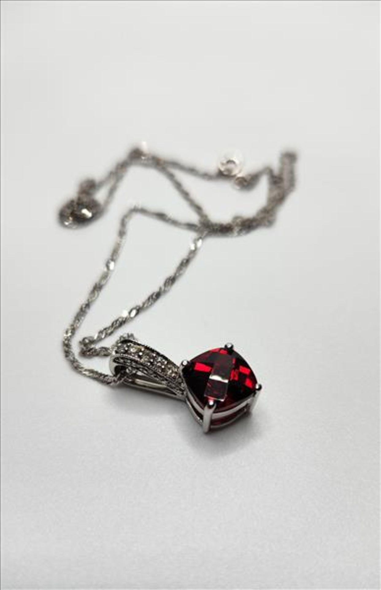 One lady’s stamped 14kt white gold Garnet and diamond pendant and 10kt white gold chain. Contained