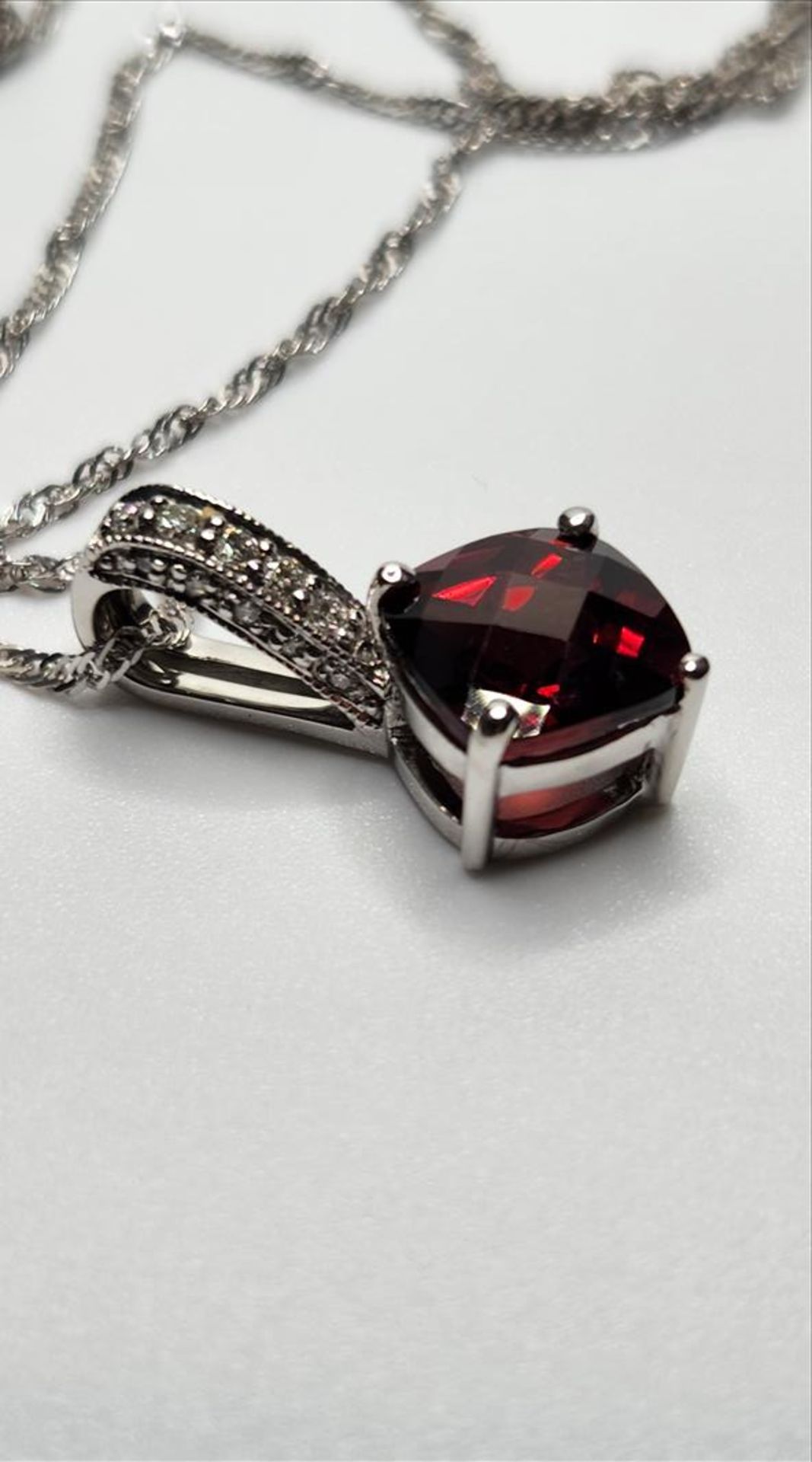 One lady’s stamped 14kt white gold Garnet and diamond pendant and 10kt white gold chain. Contained - Image 2 of 5