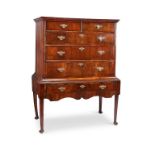 A George I walnut crossbanded and featherbanded chest on later stand