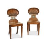 A pair of Regency carved oak shell-back hall chairs attributed to Gillows