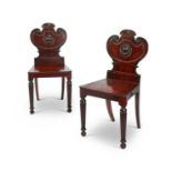 A pair of Regency mahogany carved armorial hall chairs