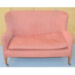 An Edwardian two seater upholstered sofa, the short mahogany legs raised on castors