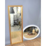 A large oval framed painted wall mirror together with a gilt mirror with decorated borders