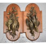 A pair of 20th century bronzed metal wall plaques in the form of game groups, mounted onto oak