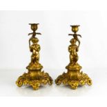 A pair of 19th century brass cherub form candlesticks, raised on four feet, 27cm high.