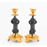 A pair of 19th century cherub candlesticks with cherubs sitting on a rock in black and gold