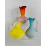 Three vintage opaque glass jugs, each in graduated colours, with frilled rims, of differing forms.