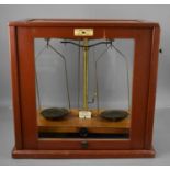 A 19th century set of scales in a glass case, with sliding front, by W&J George & Becker Ltd,