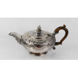 A Georgian silver teapot, embossed with foliate scrollwork, the spout with a face mask, 19toz.