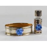 A silver napkin ring, and a silver & glass bottle, both bearing forget me not porcelain flowers.