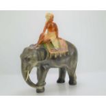 A kitsch ceramic figurine of young boy riding an elephant.