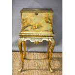 A Chinoiserie cabinet on stand, the laquered and painted fall front opens to reveal a fitted