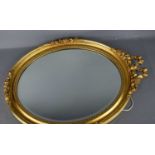 An oval giltwood wall mirror, with bow form crested top, 67cm high.