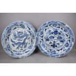 A pair of large and impressive blue and white Chinese chargers, one decorated with a dragon