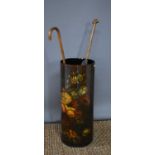 A vintage black lacquered umbrella stand, painted with a floral group and containing two umbrellas.