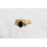 An 18ct gold, diamond and sapphire ring, the two illusion set diamonds flanking the oval cut