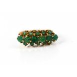 A 9ct gold and emerald dress ring, set with central row of six small graduated stones with two outer