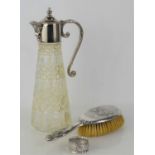 A silver backed hairbrush, decorated with cherubs, a silver napkin ring and a claret jug with plated