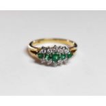 A 9ct gold emerald and diamond ring, the five graduated emeralds flanked by rows of diamonds, in a