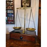 A 19th century set of shopkeepers brass scales, raised on a mahogany base with single drawer.