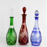 Three Bohemian cut glass decanters in green blue and red with original stoppers.