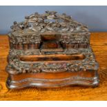 A 19th century Blackforest inkwell, carved with leaves and berries, having a central inkstand,