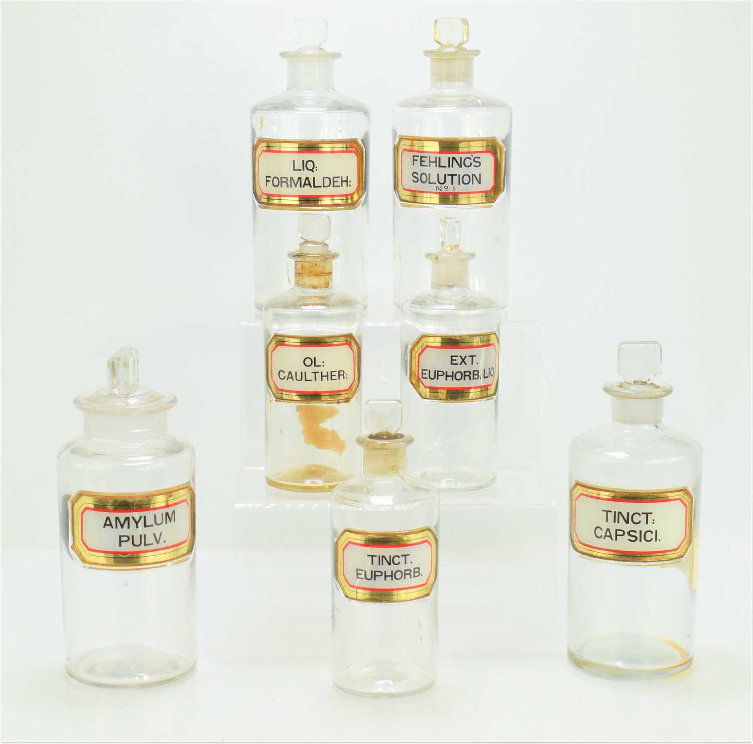 A group of seven antique clear glass apothecary bottles, bearing latin labels, the tallest