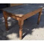 An antique pine kitchen table with single drawer and turned legs.