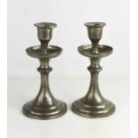 A pair of pewter candlesticks, with a hammered finish, the candle sockets raised within drip