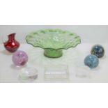 A group of glass paperweights, a Whitefriars style red jug and a green glass fruit bowl with wavy