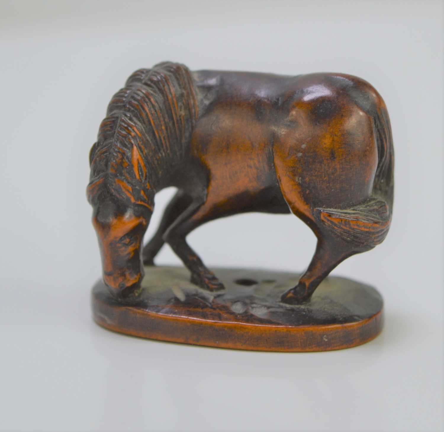 An early 20th century Japanese boxwood netsuke, in the form of a grazing horse, 3.1cm high.