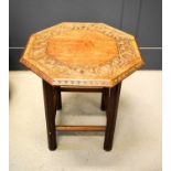 An oak occasional table with an octagonal carved top depicting a stylised floral border, 52cm high