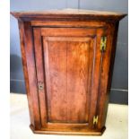 A 19th century oak corner cupboard with a fielded panel door enclosing ogee shaped shelves, 120cm