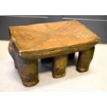 An African carved stool with chip carved decoration, raised on three pairs of elephant form legs.
