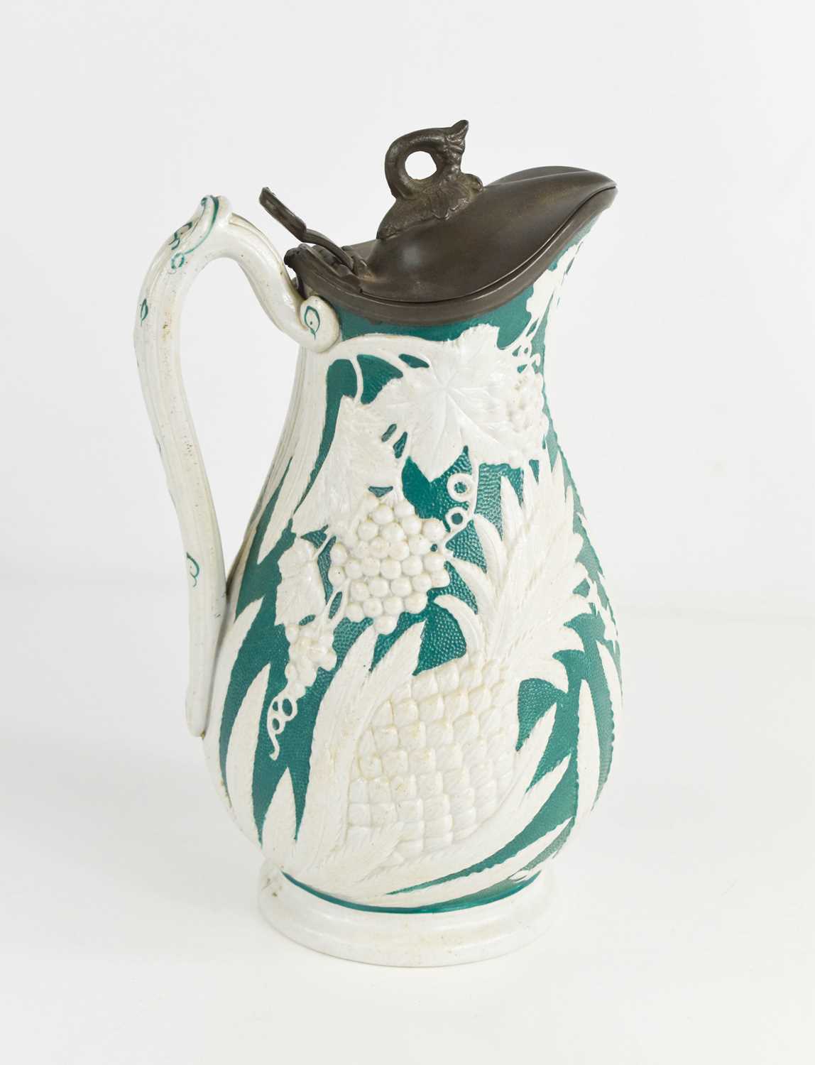 A 19th century stoneware jug, decorated with white pineapples against a green ground, with pewter