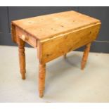 An antique pine drop leaf kitchen table with a single drawer, 74cm high by 91cm by 49cm.