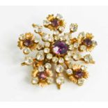 A vintage brooch of starburst flowerhead design set with amethyst coloured and white paste, 38.4mm