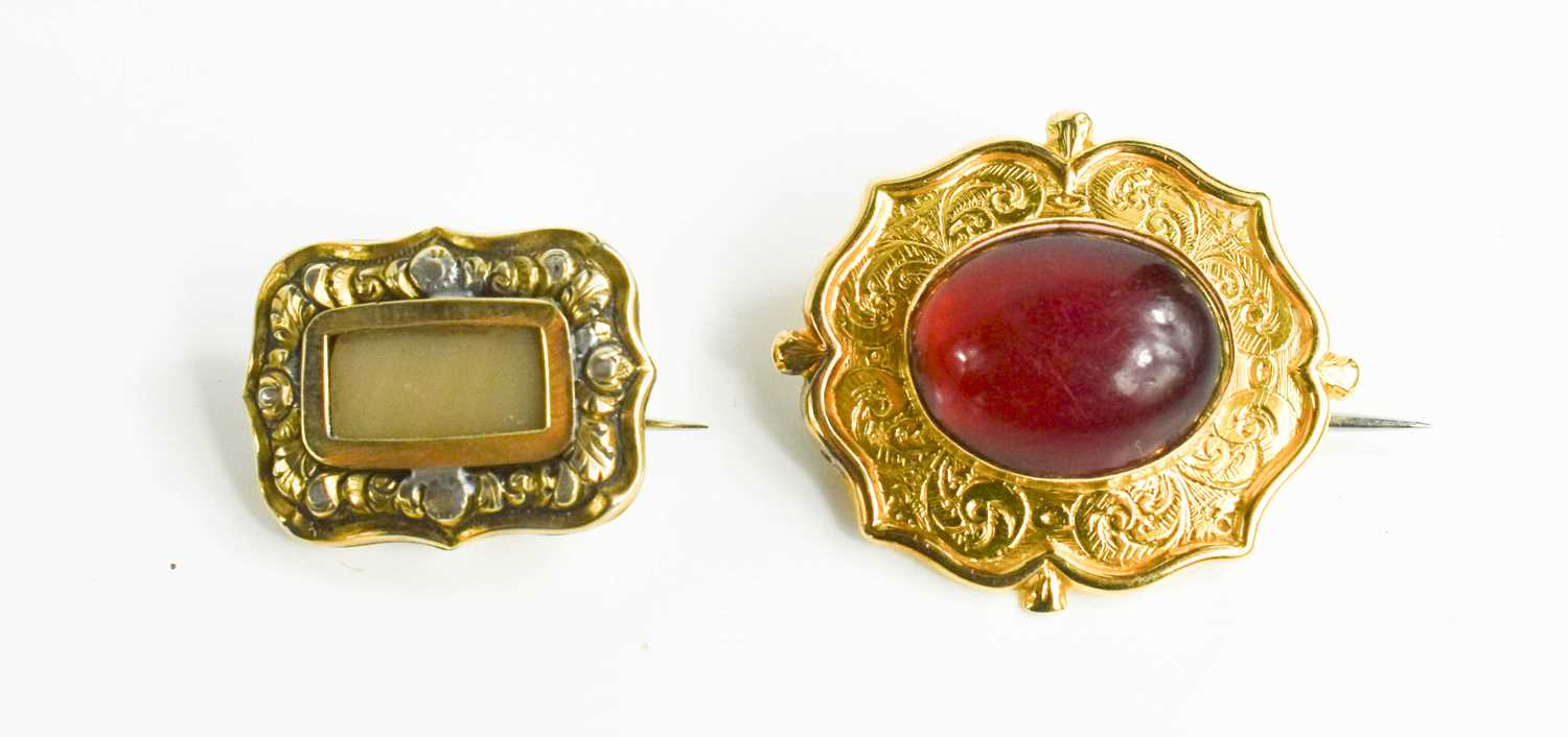 A quatrafoil brooch set with oval garnet cabouchon, with arched setting engraved foliate detail,