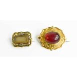 A quatrafoil brooch set with oval garnet cabouchon, with arched setting engraved foliate detail,