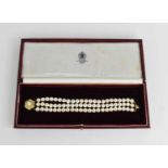 An 18ct gold and three strand pearl bracelet, by Leo de Vroomen, London 1984, the strands gathered