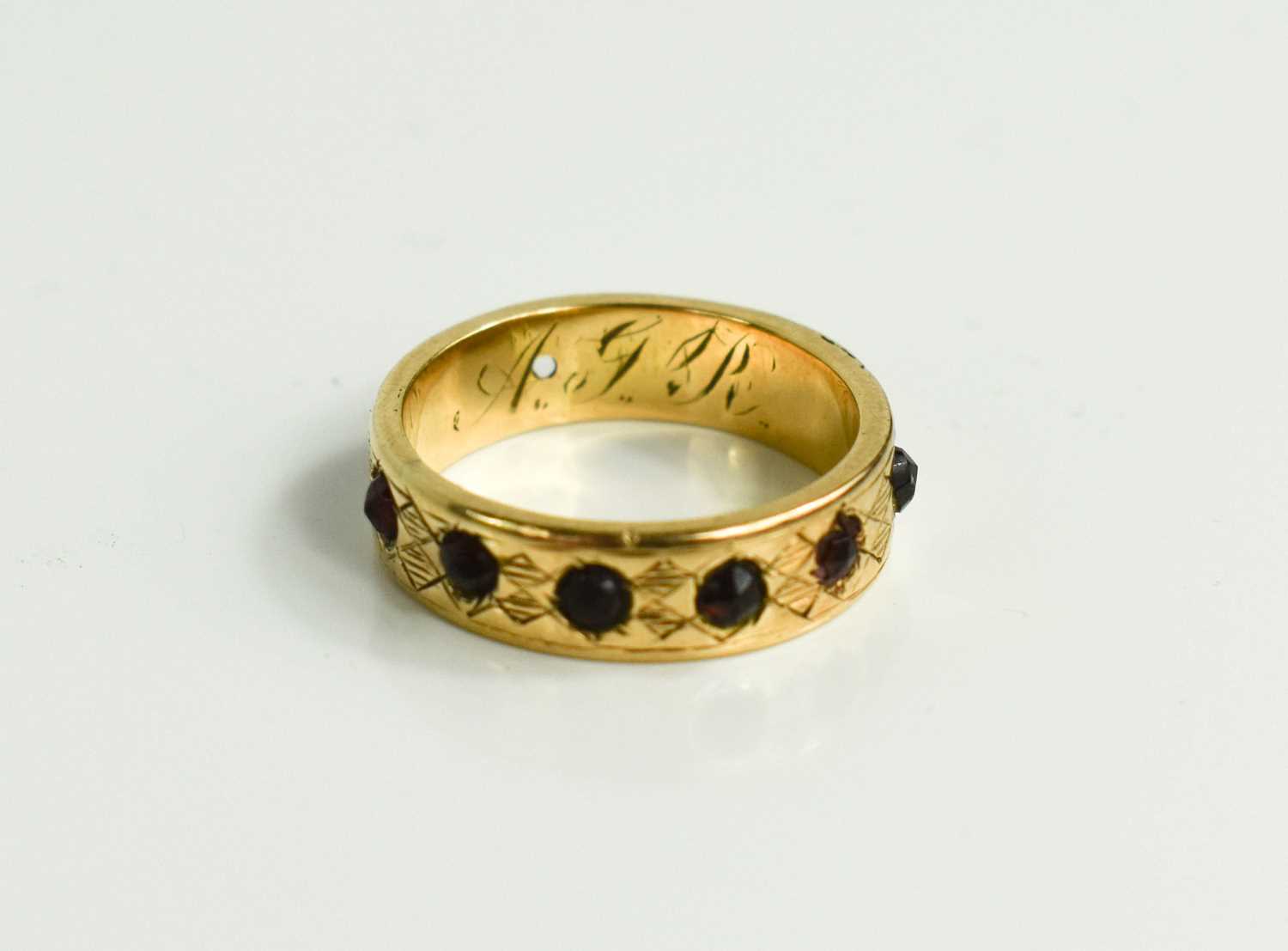 A 19th century wedding band set with garnets, foliate engraved with initials inside band, unmarked