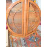 An Art Deco veneered circular form cabinet with two astrigal glazed door enclosing three glass