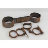 A pair of 19th century handcuffs with key and a set of 20th century prison leg shackles.