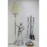 A chrome table lamp in the form of a knight holding a flaming torch together with a chrome fire side