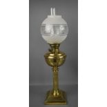 A Victorian brass and glass paraffin lamp, with etched glass shade, above an embossed bowl, reeded
