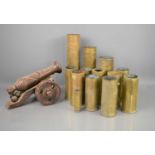 A group of mostly post WWII dated brass shells together with a wooden model cannon.