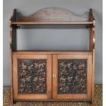 An oak Arts and Crafts period wall cabinet, the two cupboard doors carved in relief to depict oak