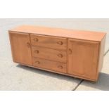 A mid-century Ercol elm sideboard, with three central drawers flanked by two cupboards raised on