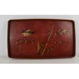 A Japanese red lacquered tea tray, painted with a bird amidst bamboo, with gilded highlights.